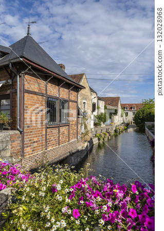French village canal flowing past historic buildings and blooming flowers 132028968