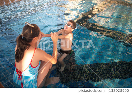 Child Smiling Brightly While Swimming With Mom At Poolside 132028990