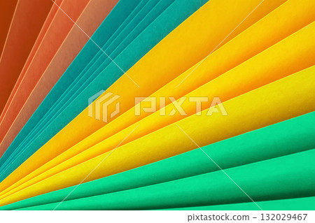 Colorful paper sheets fanned out in vibrant shades of yellow, green, orange and blue. Concept of color paper, creative background, bright design Colorful paper sheets fanned out in vibrant shades of yellow, green, orange and blue. Concept of color paper, creative background, bright design 132029467