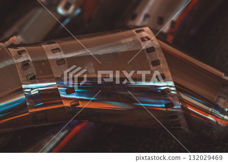 Close-up of rolled 35mm film strip with cinematic glow and light reflections. Concept of film, filmstrip, retro cinema, analog photography 132029469