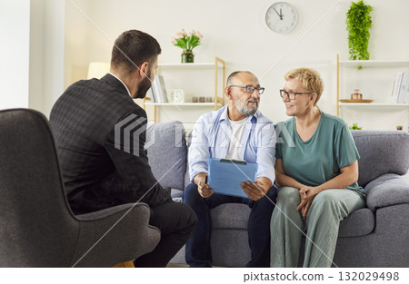 Senior couple with advisor at home reviewing financial documents, planning Senior couple with advisor at home reviewing financial documents, planning 132029498