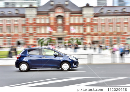 A blue car driving in front of the Marunouchi South Exit of Tokyo Station 132029658