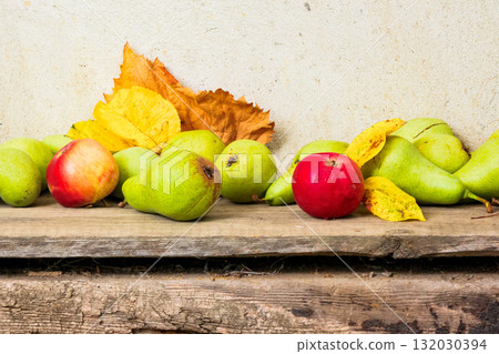 rural harvest in autumn. fruits on wooden background. fresh pears and ripe apples with yellow leaves laying on the board. rustic organic still life composition rural harvest in autumn. fruits on wooden background. fresh pears and ripe apples with yellow leaves laying on the board. rustic organic still life composition 132030394