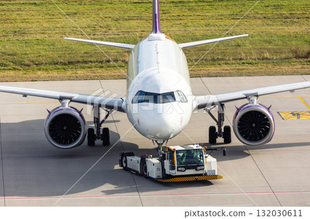 Modern regional jet aircraft towed by ground vehicle on airport taxiway tarmac under sunlight. Engine cockpit clearly visible crew performs technical operations before next scheduled flight airport 132030611