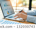 An office worker analyzes graphs on his laptop while working in office AI Generation 132030743