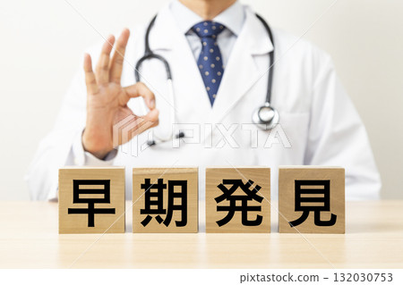 一位醫生做出「OK」手勢,手裡拿著一個寫著「早期檢測」的方塊。 一位醫生做出「OK」手勢,手裡拿著一個寫著「早期檢測」的方塊。 132030753