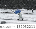 An old man walking with an umbrella on a snowy day 132032211