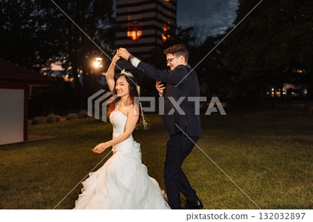 Happy interracial wedding couple dancing during outdoor reception 132032897