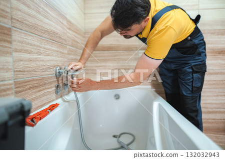 Plumber Installing Faucet on Bathtub in Bathroom Plumber Installing Faucet on Bathtub in Bathroom 132032943