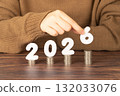 2026 New year saving money and financial planning concept. Female hands putting white number 2026 on stack of coins. Creative idea for business growth, tax payment, investment and banking. 132033076