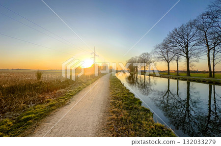 Experience the Scenic Sunrise by the Tranquil Canal Path, filled with beauty and serenity 132033279