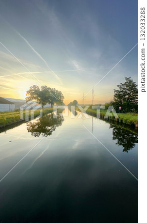 A Serene Sunrise Reflection Casts a Beautiful Image Over a Calm and Peaceful Canal 132033288