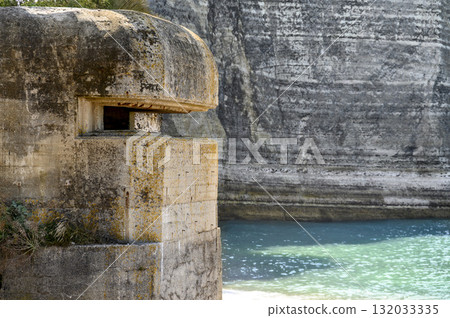 An old abandoned concrete pillbox on the ocean shore near high rock cliffs. Color horizontal photo An old abandoned concrete pillbox on the ocean shore near high rock cliffs. Color horizontal photo 132033335