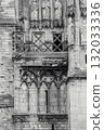 A wall of an old Catholic church with a balcony and various decorative stone elements. Vertical black and white photo 132033336