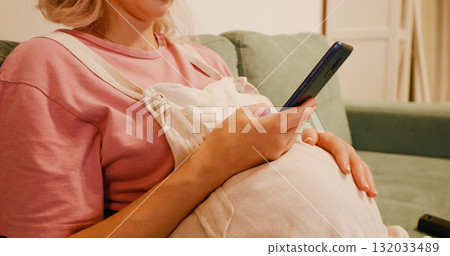 No face pregnant woman using phone and stroking her tummy. No face pregnant woman using phone and stroking her tummy. 132033489