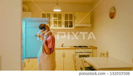 Woman opening refrigerator and eating cake at home. Woman opening refrigerator and eating cake at home. 132033506
