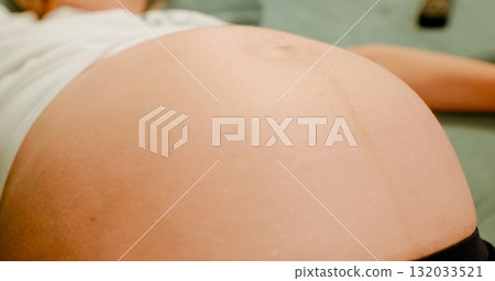 Women are observing the movement of the abdominal surface due to the movement of the unborn child. Women are observing the movement of the abdominal surface due to the movement of the unborn child. 132033521
