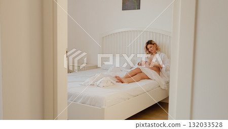 Pregnant woman indoors lying in the bed caressing her belly. 132033528