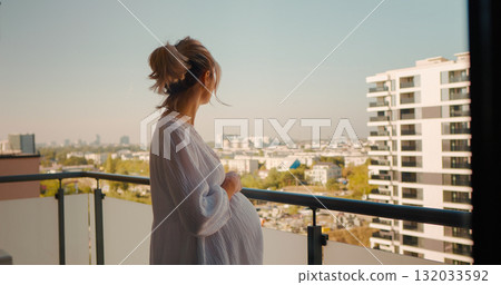 Woman coming outside at balcony to enjoy the view from the hotel while touching her tummy. Woman coming outside at balcony to enjoy the view from the hotel while touching her tummy. 132033592