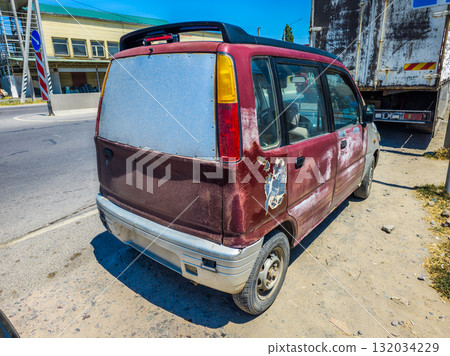 Damaged car parked on urban street during daytime 132034229