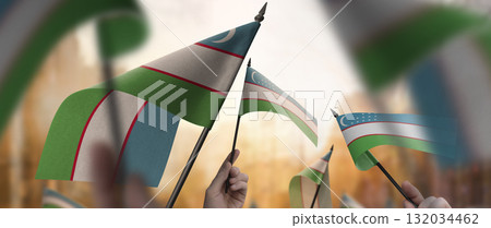 Uzbekistan flags in their hands on a blurred urban background 132034462