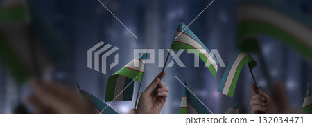 Uzbekistan flags in their hands on a blurred urban background Uzbekistan flags in their hands on a blurred urban background 132034471
