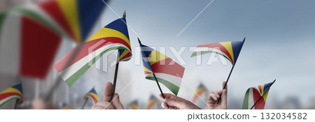 Seychelles flags in their hands on a blurred urban background Seychelles flags in their hands on a blurred urban background 132034582