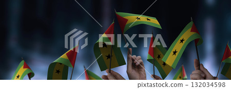 Sao Tome and Principe flags in their hands on a blurred urban background 132034598