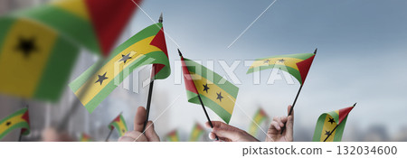 Sao Tome and Principe flags in their hands on a blurred urban background 132034600