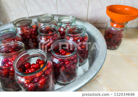 Canning cherries in glass jars indoors during daytime preparation Canning cherries in glass jars indoors during daytime preparation 132034696