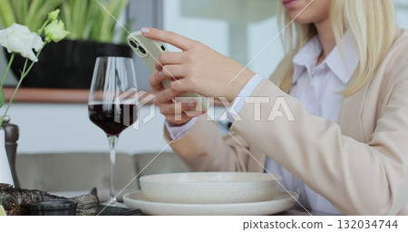 Young woman hands using a smartphone while sitting at a cafe table. Woman texting on phone in cafe. Unrecognizable female using smartphone. Young woman hands using a smartphone while sitting at a cafe table. Woman texting on phone in cafe. Unrecognizable female using smartphone. 132034744