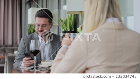 Young couple ordering food online at restaurant table. Looking online cafe menu together. Technology device concept. Young couple ordering food online at restaurant table. Looking online cafe menu together. Technology device concept. 132034745