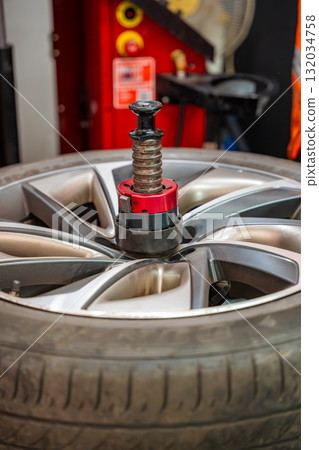 Car wheel positioned on a tire changing machine before removing the tire from the rim. Seasonal tire replacement process at an auto service during winter preparation. 132034758
