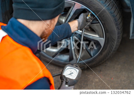 Worker checking tire pressure with gauge after seasonal wheel replacement. Final step of winter tire preparation in auto service in Czech Republic. Worker checking tire pressure with gauge after seasonal wheel replacement. Final step of winter tire preparation in auto service in Czech Republic. 132034762