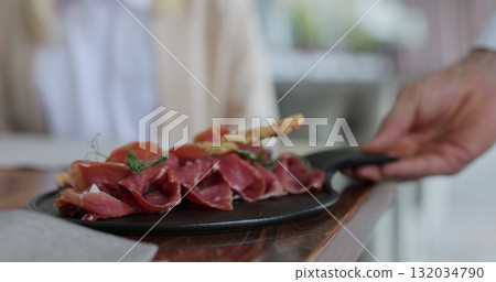 Couple sitting by table in a cafe. Waiter comes to them and brings the dish. Customer service. 132034790
