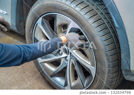 Mechanic closing tire valve after checking pressure during seasonal tire change. Essential step of car maintenance before winter in Czech Republic. 132034799