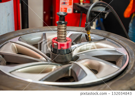 Inflating a car tire on a tire changing machine during seasonal wheel replacement. Critical step for proper pressure and road safety before winter driving. Inflating a car tire on a tire changing machine during seasonal wheel replacement. Critical step for proper pressure and road safety before winter driving. 132034843
