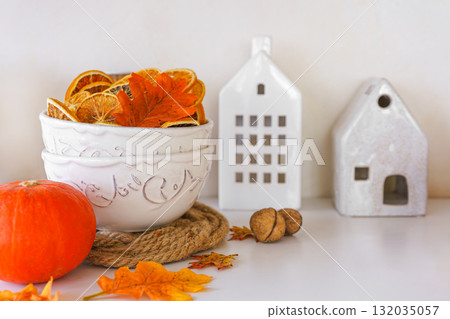 Autumn decoration with dried oranges, leaves, orange pumpkin in kitchen setting on white background 132035057