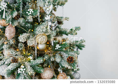 Snowy Christmas tree branch with festive lights and decorative gold and silver ornaments close up Snowy Christmas tree branch with festive lights and decorative gold and silver ornaments close up 132035080