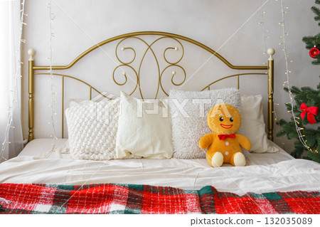 Festive bedroom, cozy bed with gingerbread plush toy, decorative pillows and Christmas tree Festive bedroom, cozy bed with gingerbread plush toy, decorative pillows and Christmas tree 132035089