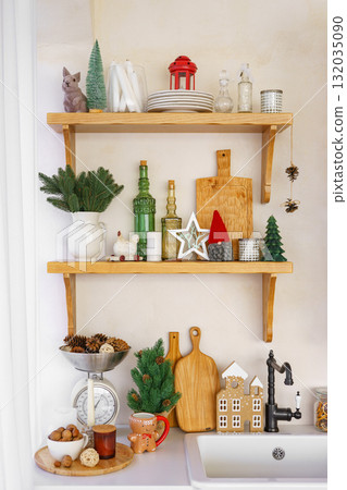 Christmas kitchen interior decorated with festive shelf decor, gingerbread mug and pine branches 132035090
