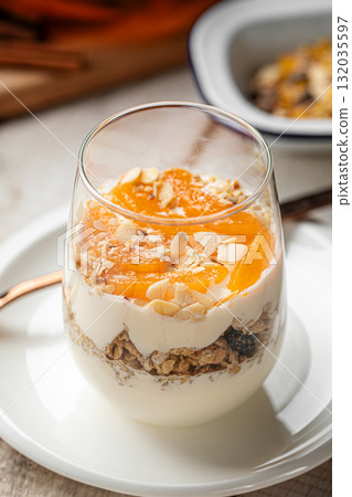 Yogurt dessert with granola and apricots in glass 132035597