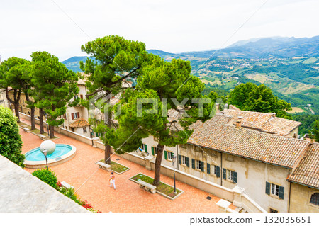 San Marino old street architecture in center city. Houses wall roof and window. Green pines trees San Marino old street architecture in center city. Houses wall roof and window. Green pines trees 132035651