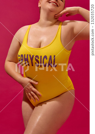 Smiling plus-size woman in yellow swimsuit posing confidently in bright fashion editorial style 132035720