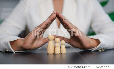 Businesswoman protecting family with hands showing insurance and safety concept 132036338