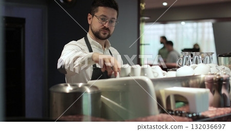 Barista makes coffee in a coffee shop. Bartender preparing coffee at the bar in a restaurant. Coffee shop concept. Barista makes coffee in a coffee shop. Bartender preparing coffee at the bar in a restaurant. Coffee shop concept. 132036697
