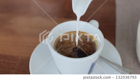 Pouring milk into coffee cup. Coffee with froth close up. Hot coffee in the morning. Pouring milk into coffee cup. Coffee with froth close up. Hot coffee in the morning. 132036793