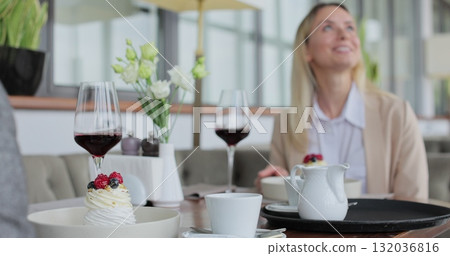Close up waiter and coffee on a tray, walking to a customer in or restaurant cafe. Man and woman talking together and enjoying evening. 132036816