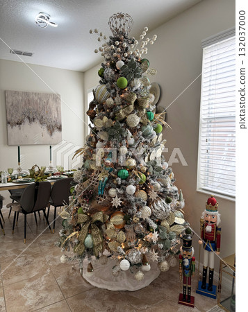 A tall Christmas tree decorated in gold and green stands beside classic nutcracker figures. The festive interior combines tradition, color, and elegant design. 132037000