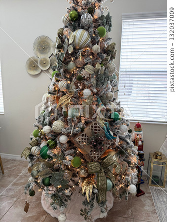 A close-up view of a luxurious Christmas tree filled with detailed ornaments, ribbons, and lights. The gold and green color palette creates an elegant holiday look. A close-up view of a luxurious Christmas tree filled with detailed ornaments, ribbons, and lights. The gold and green color palette creates an elegant holiday look. 132037009